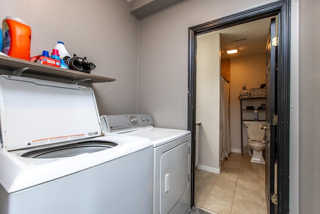 clothes washing area with washing machine and dryer and light tile patterned floors