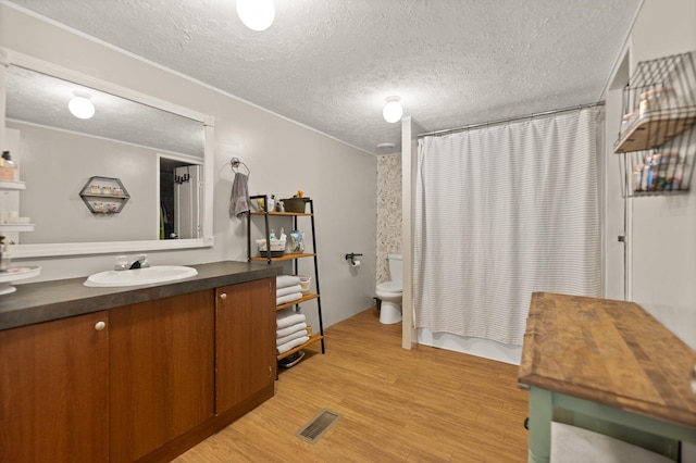 bathroom featuring wood-type flooring, a textured ceiling, vanity, and toilet