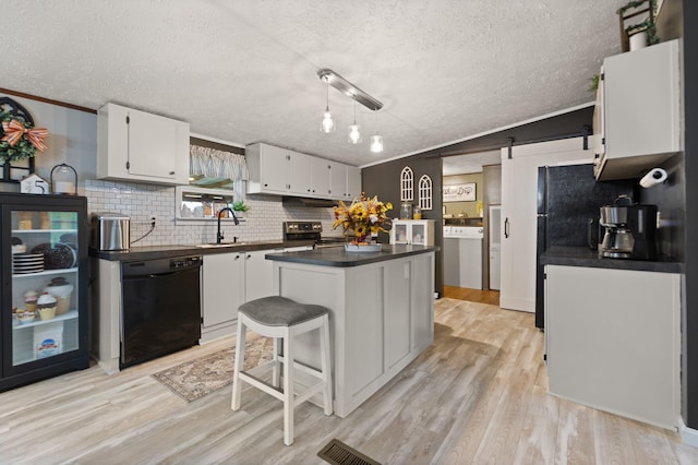 kitchen with white cabinets, black dishwasher, a center island, and a barn door