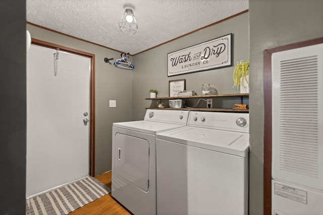 laundry area with ornamental molding, hardwood / wood-style flooring, washer and dryer, and a textured ceiling