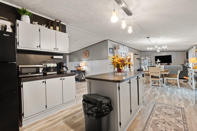 kitchen featuring white cabinets, a textured ceiling, and light wood-type flooring