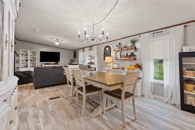 dining room with an inviting chandelier, ornamental molding, a textured ceiling, and light hardwood / wood-style floors