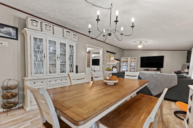 dining room with an inviting chandelier, a textured ceiling, light wood-type flooring, and ornamental molding