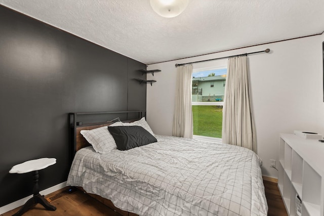 bedroom with a textured ceiling and dark hardwood / wood-style flooring