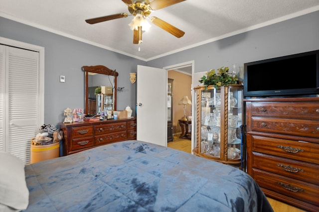 bedroom featuring a closet, light wood-type flooring, a textured ceiling, ceiling fan, and ornamental molding