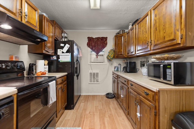 kitchen with black appliances, light hardwood / wood-style floors, and a textured ceiling