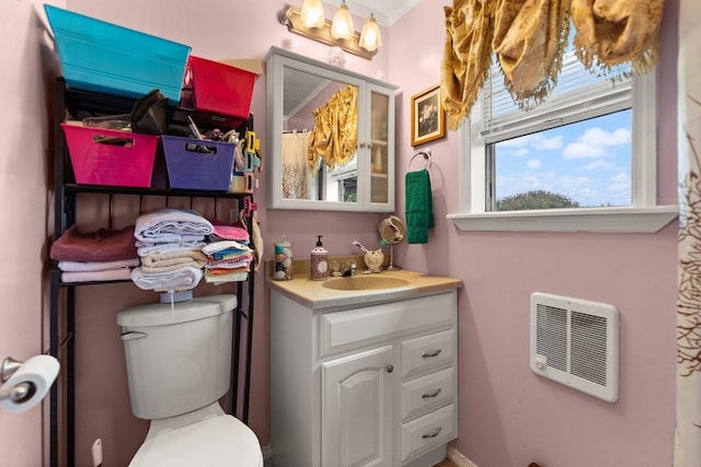 bathroom featuring vanity, heating unit, and toilet