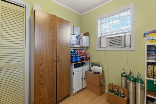 clothes washing area featuring cooling unit, light hardwood / wood-style floors, and crown molding