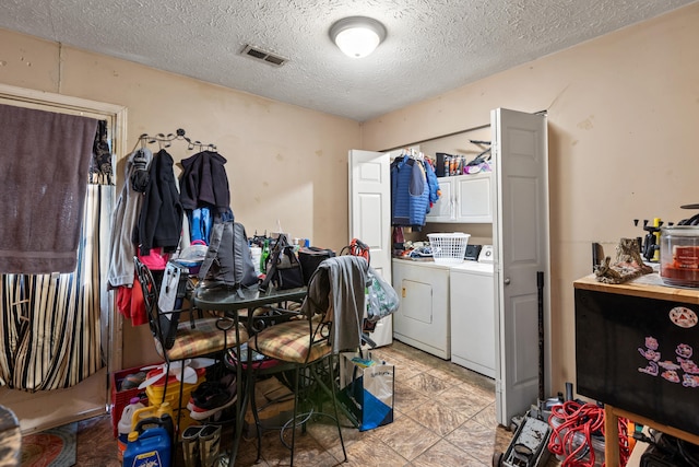 laundry room featuring independent washer and dryer, a textured ceiling, and cabinets