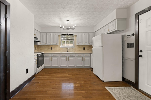 kitchen featuring a chandelier, dark wood-type flooring, white appliances, and tasteful backsplash