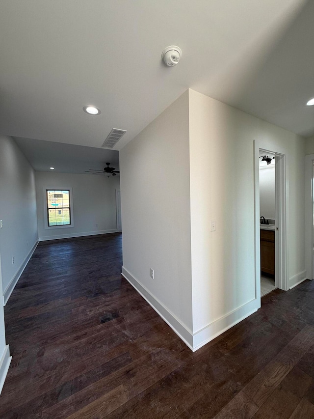 spare room with visible vents, a ceiling fan, dark wood-type flooring, and baseboards