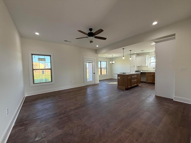 kitchen with dark hardwood / wood-style floors, ceiling fan with notable chandelier, hanging light fixtures, a kitchen island, and dishwasher