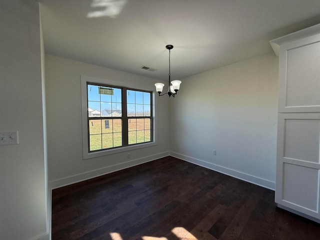 unfurnished room with an inviting chandelier, dark wood-type flooring, baseboards, and visible vents