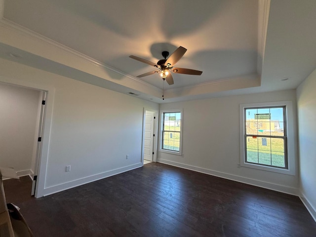 spare room with dark wood finished floors, a tray ceiling, baseboards, and ceiling fan