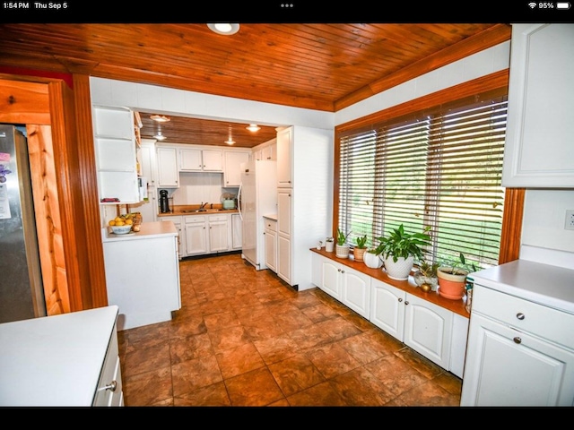 kitchen featuring white cabinets, white refrigerator, wooden ceiling, and sink