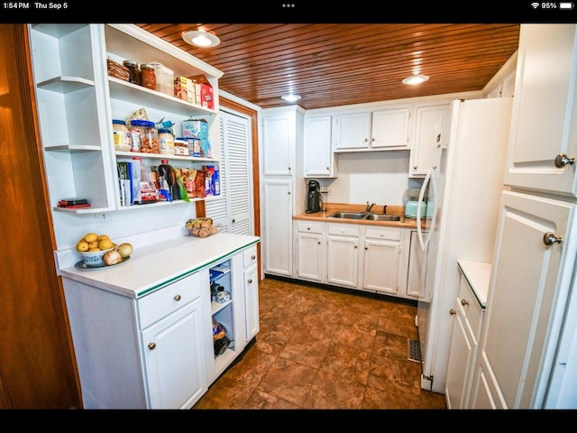 kitchen featuring white cabinets, wooden ceiling, white fridge, and sink