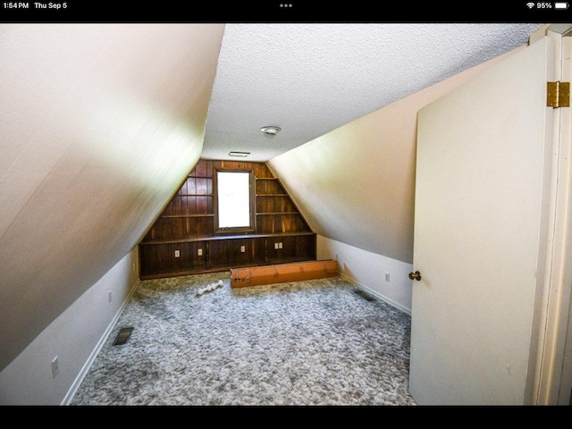 bonus room with vaulted ceiling, a textured ceiling, and carpet flooring