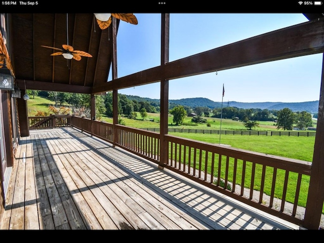 wooden terrace featuring a lawn, a mountain view, ceiling fan, and a rural view