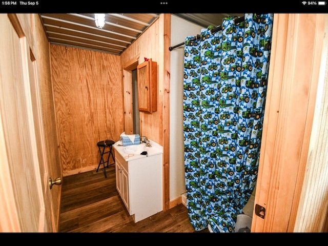 bathroom featuring a shower with shower curtain, vanity, wooden walls, and hardwood / wood-style flooring