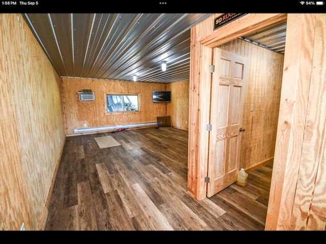 interior space with a baseboard radiator, wooden walls, hardwood / wood-style floors, and an AC wall unit