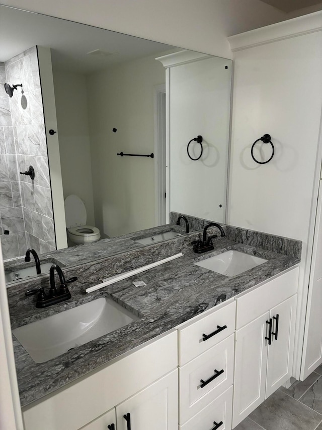 bathroom with vanity, tiled shower, and toilet