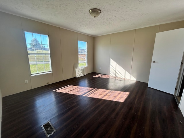 empty room featuring a textured ceiling and dark hardwood / wood-style floors