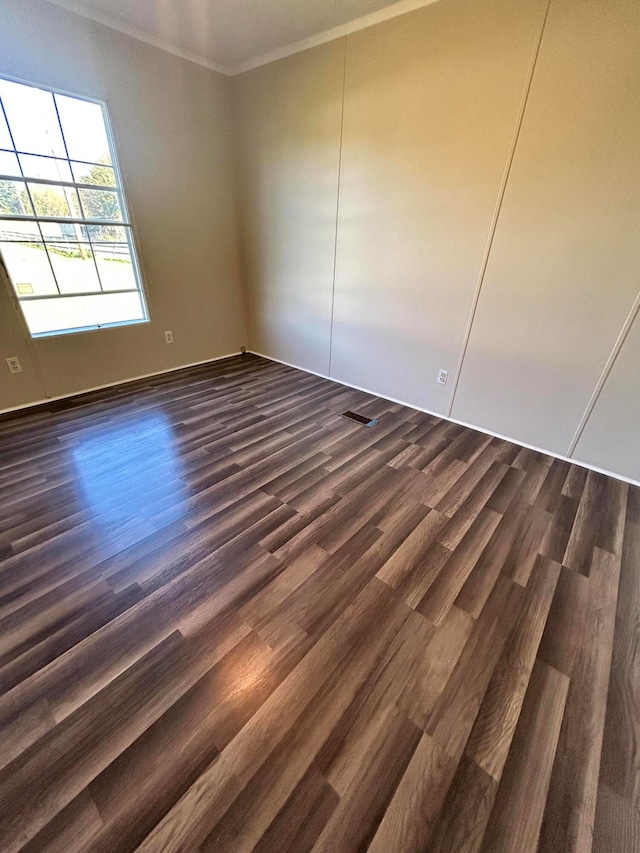 unfurnished room featuring ornamental molding and dark hardwood / wood-style flooring