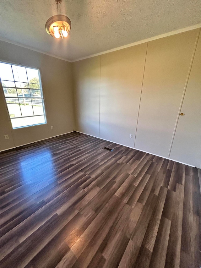 unfurnished room featuring ornamental molding, a textured ceiling, and dark hardwood / wood-style floors