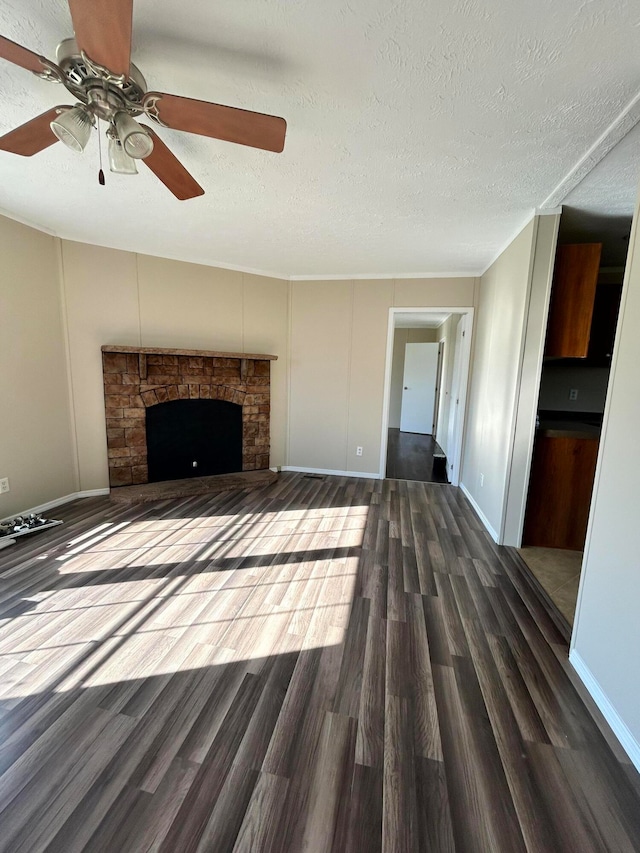 unfurnished living room with ceiling fan, a fireplace, a textured ceiling, and dark hardwood / wood-style flooring