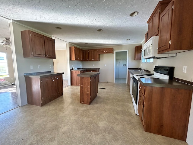 kitchen featuring a kitchen island, sink, a textured ceiling, white appliances, and ceiling fan