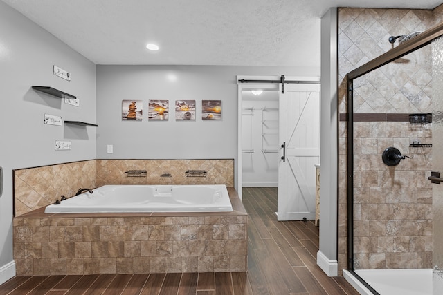 bathroom with a textured ceiling, hardwood / wood-style flooring, and independent shower and bath