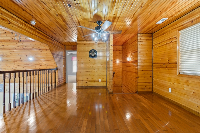 unfurnished room with wood ceiling, hardwood / wood-style flooring, wooden walls, and ceiling fan