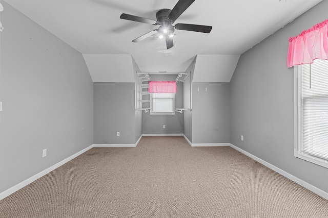 additional living space featuring a wealth of natural light, vaulted ceiling, light carpet, and ceiling fan