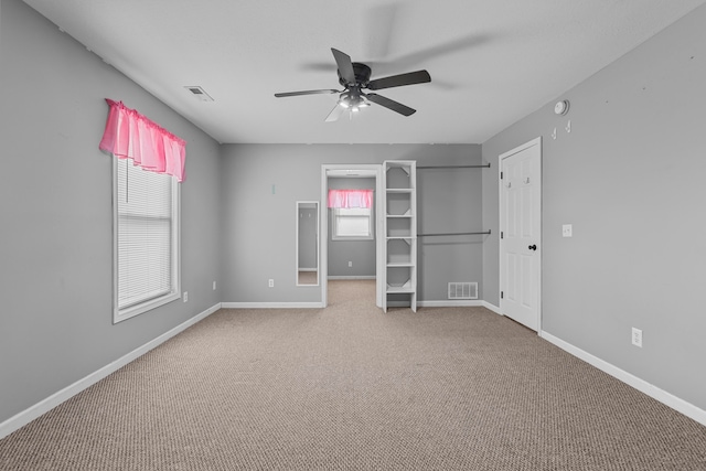 unfurnished bedroom with multiple windows, carpet flooring, and ceiling fan