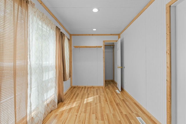 hallway with crown molding, light hardwood / wood-style floors, and wooden walls