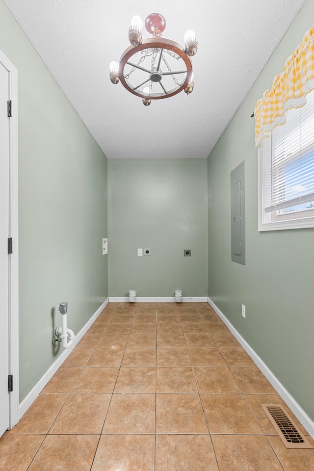 laundry area featuring light tile patterned floors, electric dryer hookup, a textured ceiling, and electric panel