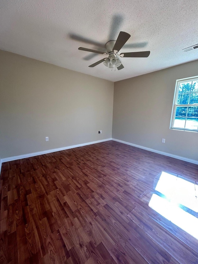 empty room with a textured ceiling, dark hardwood / wood-style flooring, and ceiling fan