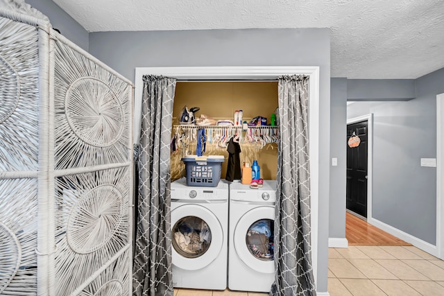 washroom featuring washing machine and clothes dryer, tile patterned flooring, and a textured ceiling