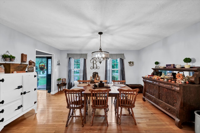 dining room featuring a textured ceiling, an inviting chandelier, and light hardwood / wood-style flooring