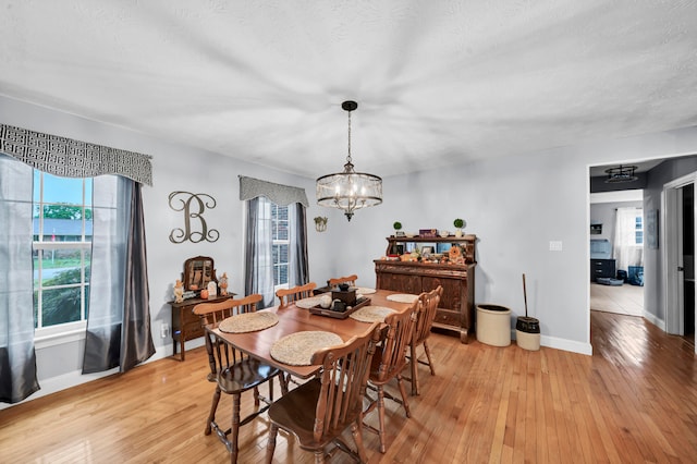 dining room featuring light hardwood / wood-style flooring, a notable chandelier, and plenty of natural light