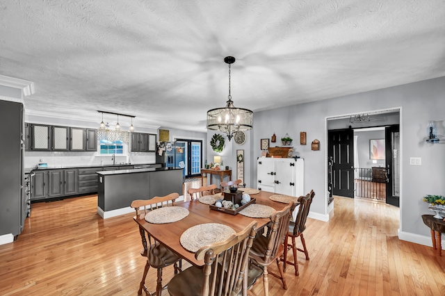 dining space with a textured ceiling, light wood-type flooring, and sink