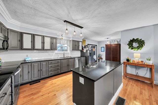 kitchen with sink, a kitchen island, light hardwood / wood-style flooring, gray cabinets, and appliances with stainless steel finishes