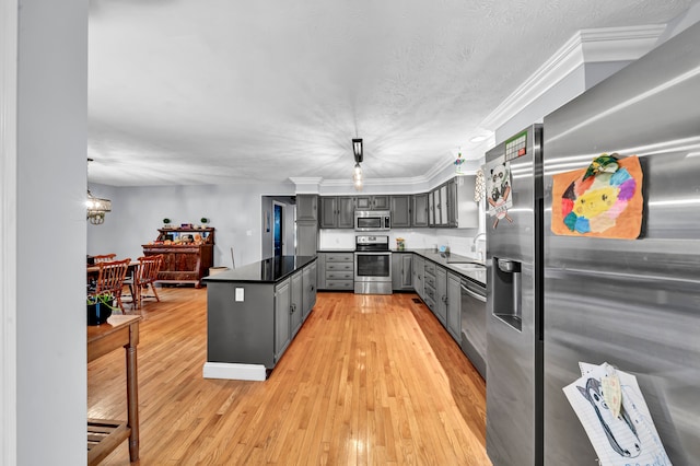 kitchen featuring hanging light fixtures, gray cabinetry, stainless steel appliances, light hardwood / wood-style flooring, and ornamental molding