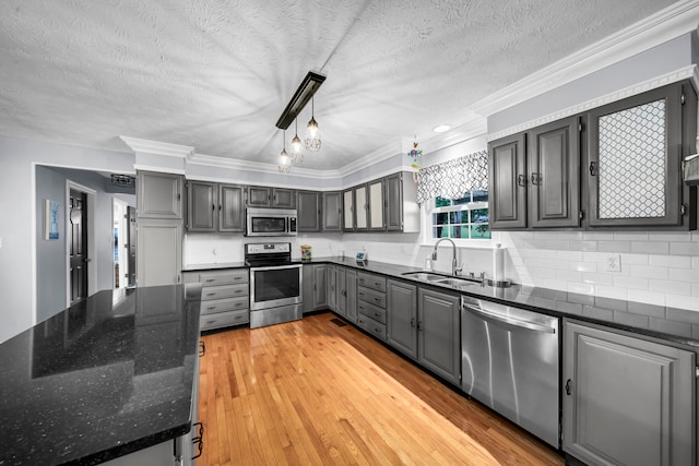 kitchen with sink, gray cabinetry, stainless steel appliances, light wood-type flooring, and crown molding