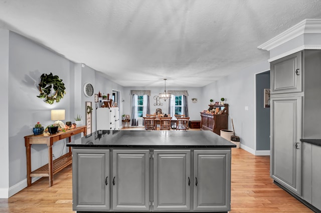 kitchen with gray cabinetry, hanging light fixtures, light hardwood / wood-style floors, and a center island