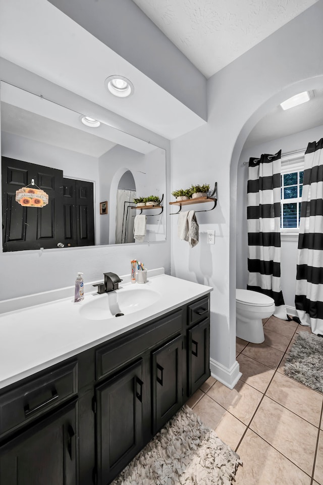 bathroom featuring a textured ceiling, tile patterned flooring, vanity, and toilet