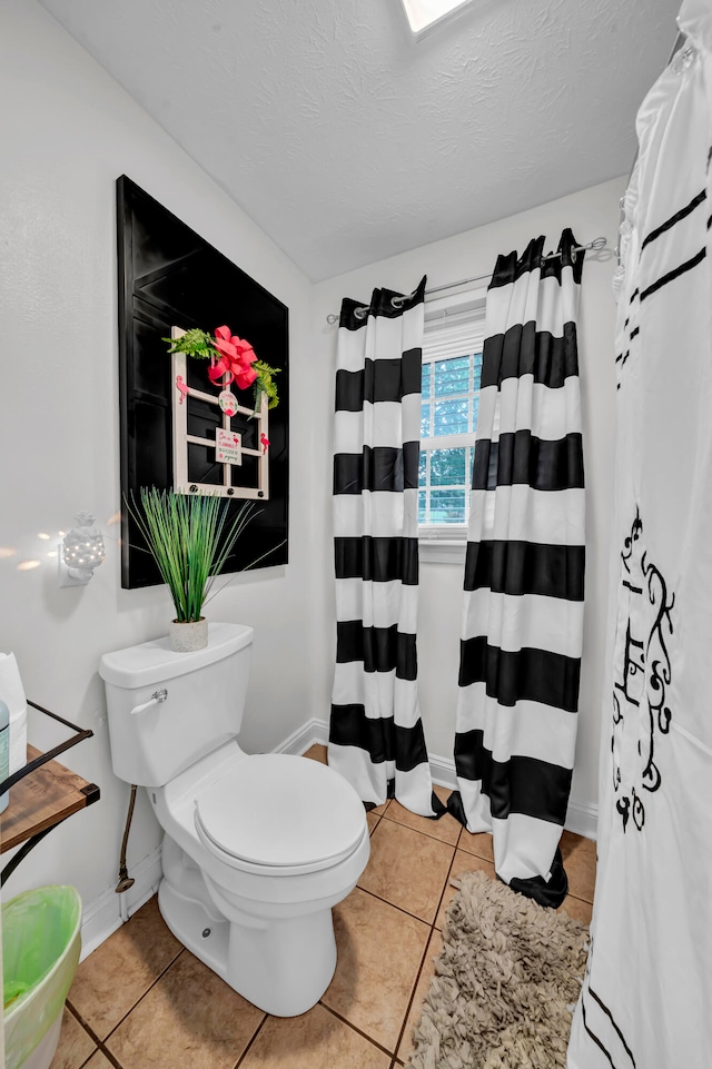 bathroom featuring tile patterned flooring, a textured ceiling, and toilet