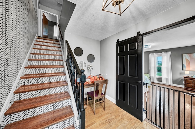 entrance foyer with a barn door, a textured ceiling, and light hardwood / wood-style floors