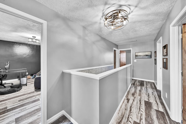 hallway with a textured ceiling and wood-type flooring