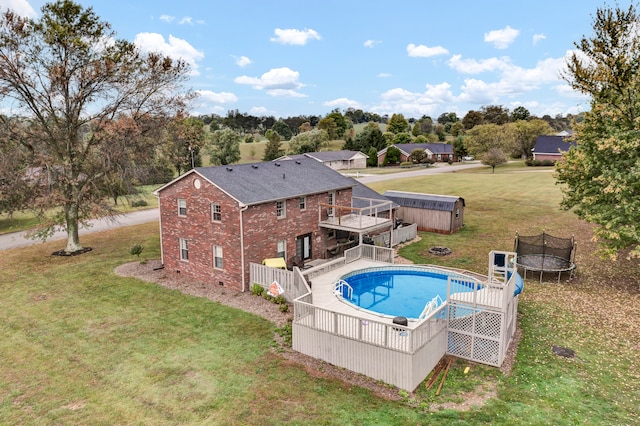 view of swimming pool featuring a trampoline, a wooden deck, and a yard